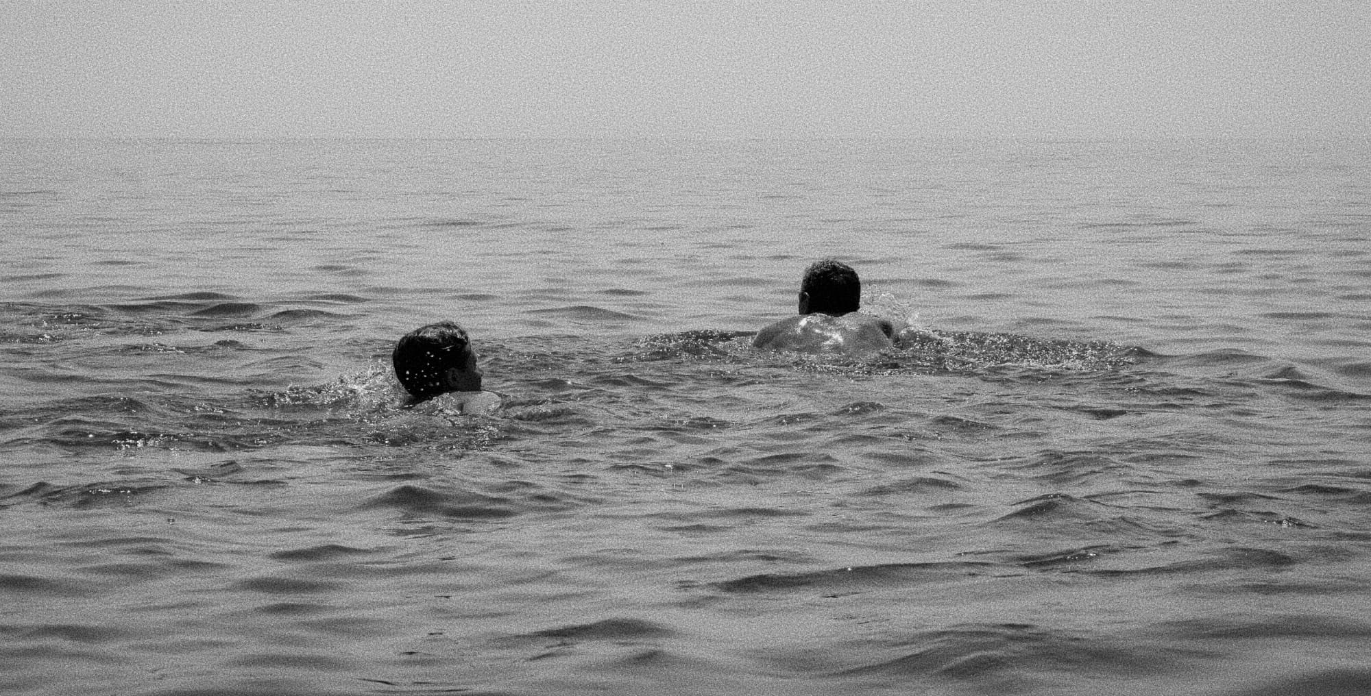 Two people swimming in the sea, black and white